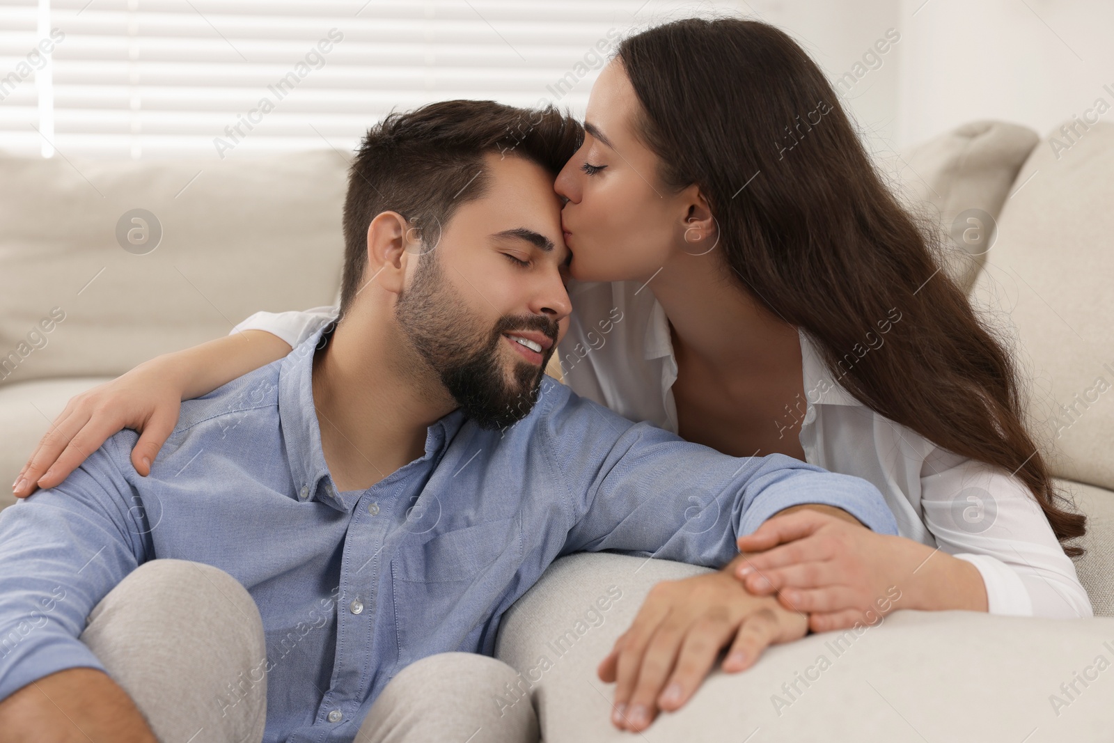 Photo of Young woman kissing her boyfriend at home