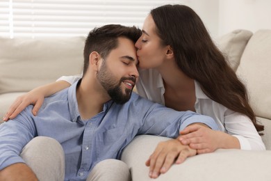 Young woman kissing her boyfriend at home