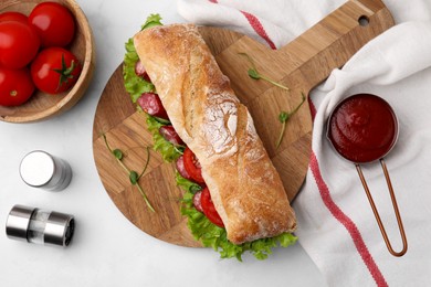 Photo of Delicious sandwich with sausages, vegetables and ingredients on white table, flat lay