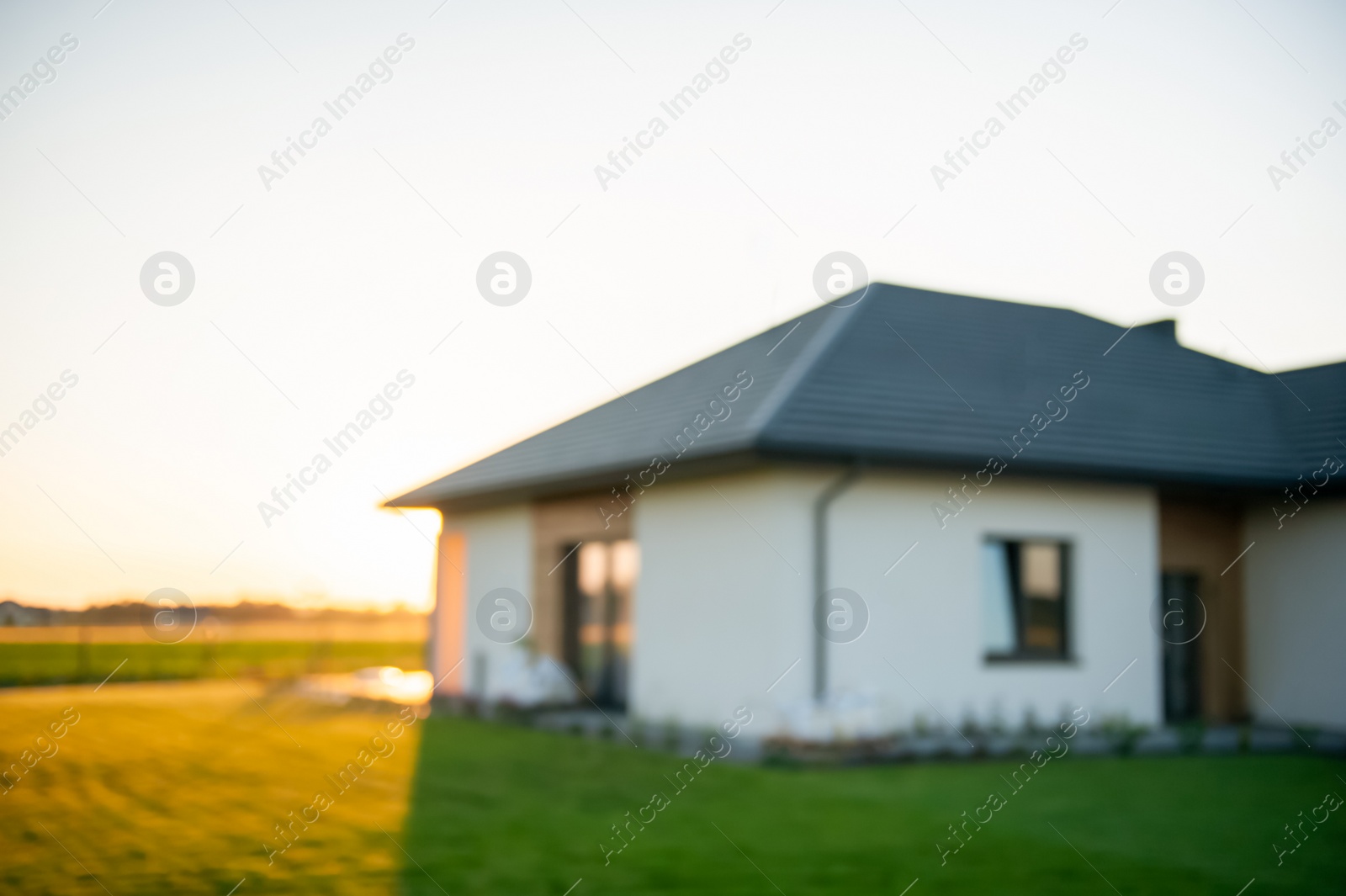 Photo of Blurred view of beautiful house with green lawn on sunny day