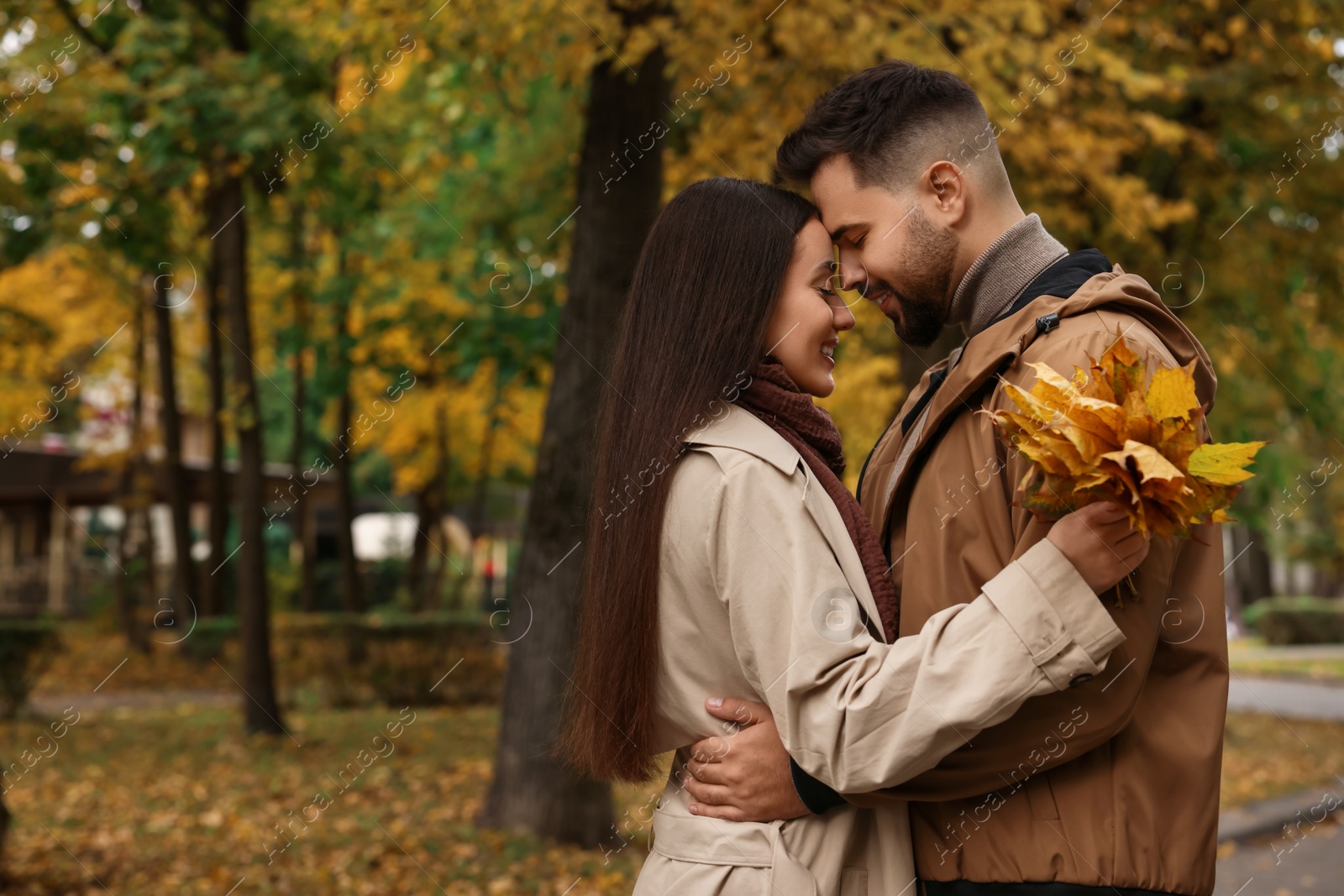 Photo of Romantic young couple spending time together in autumn park, space for text