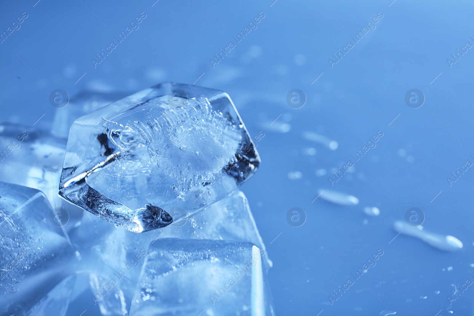 Photo of Transparent ice cubes on color background, closeup. Space for text