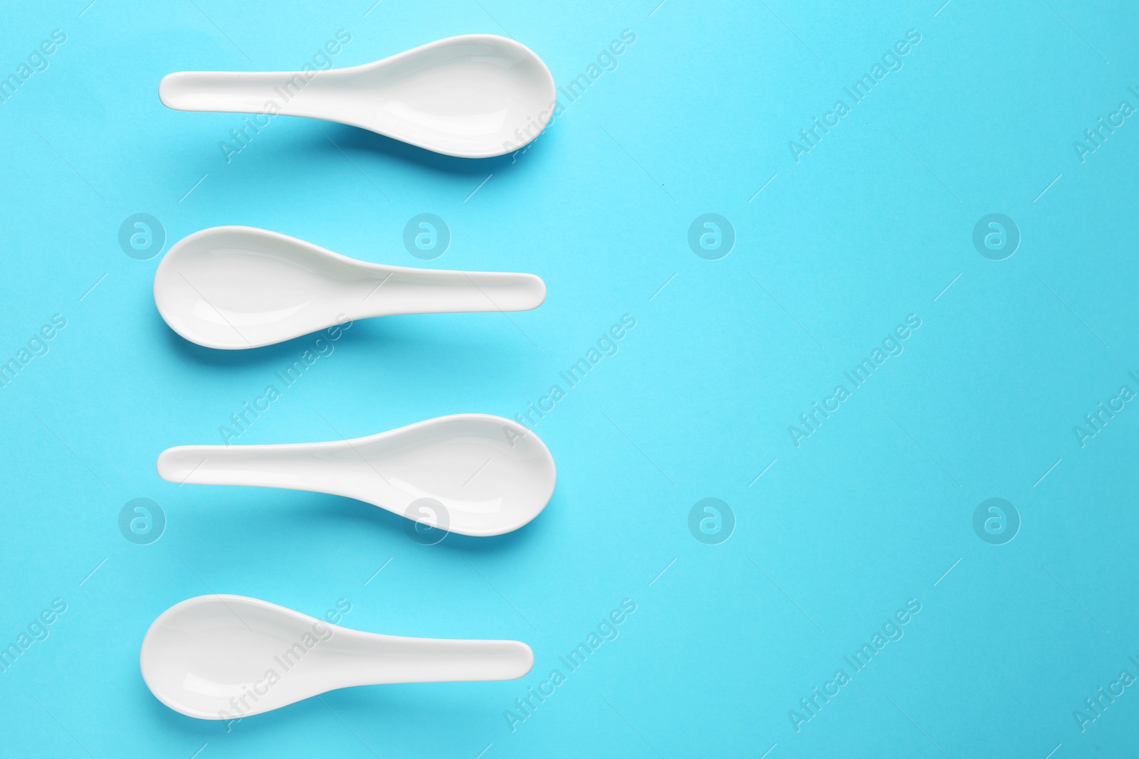 Photo of Miso soup spoons on blue background, flat lay. Space for text