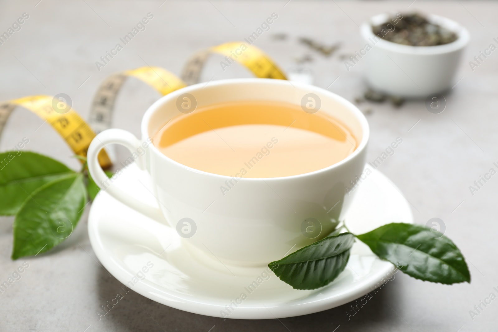 Photo of Cup of herbal diet tea and measuring tape on light table