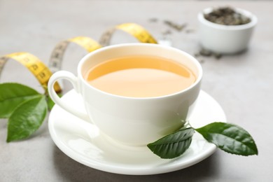 Photo of Cup of herbal diet tea and measuring tape on light table