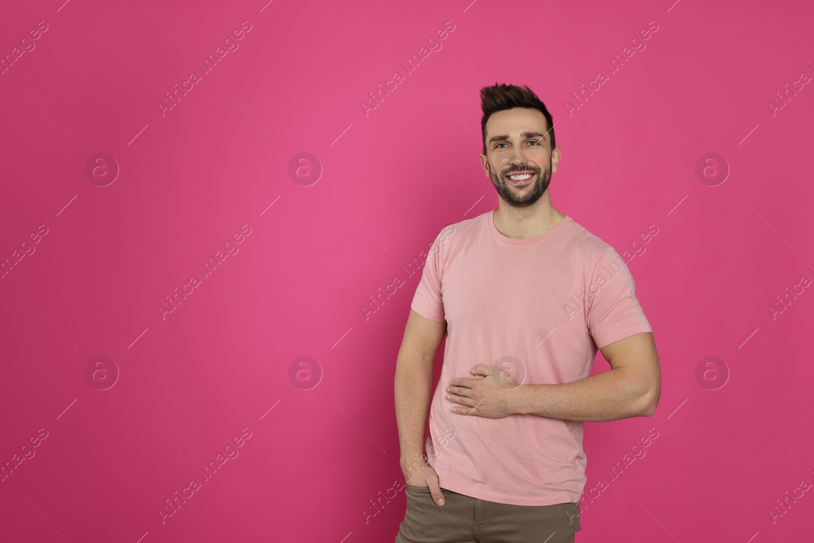 Photo of Happy man touching his belly on pink background, space for text. Concept of healthy stomach