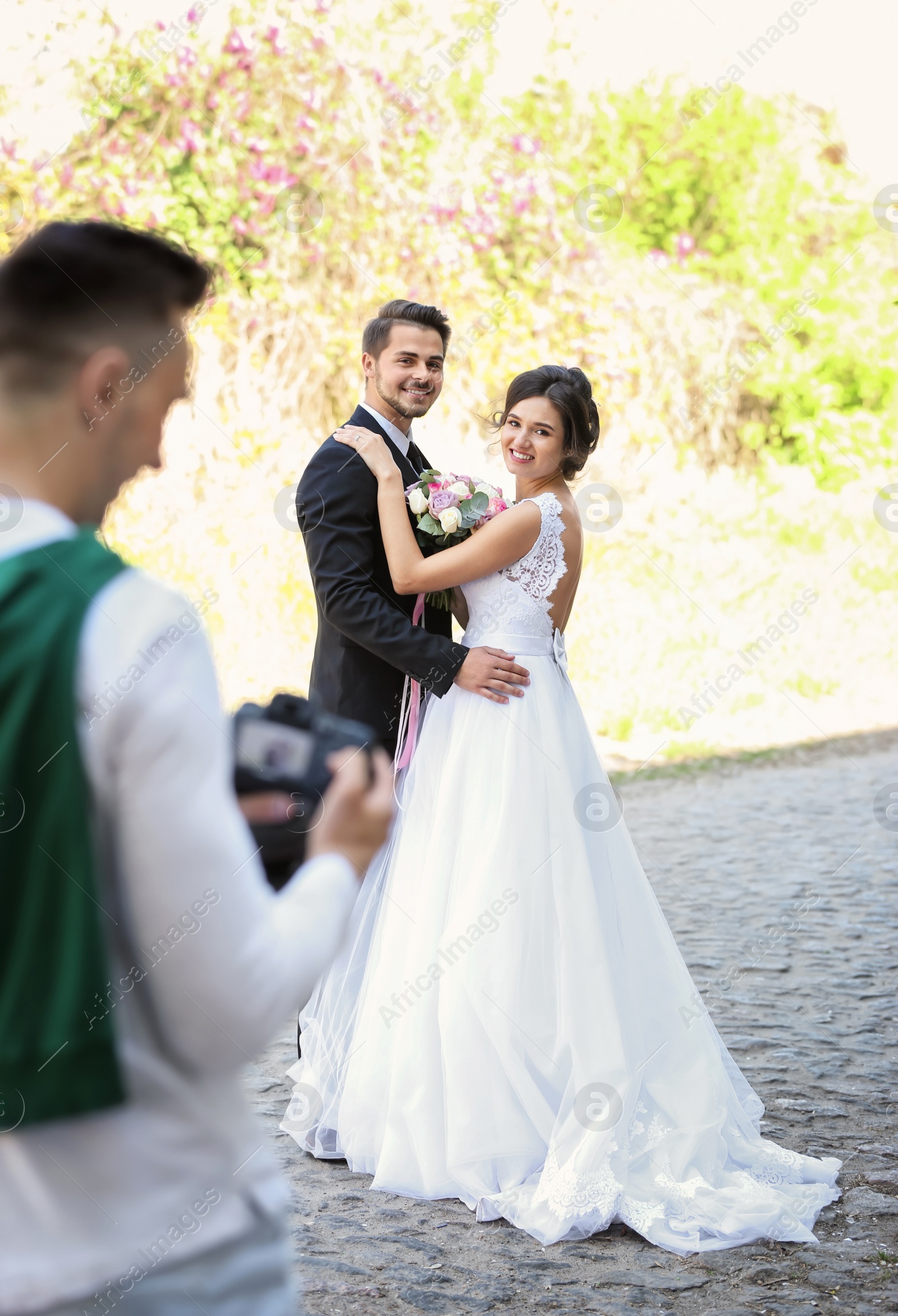 Photo of Wedding couple and professional photographer with camera, outdoors
