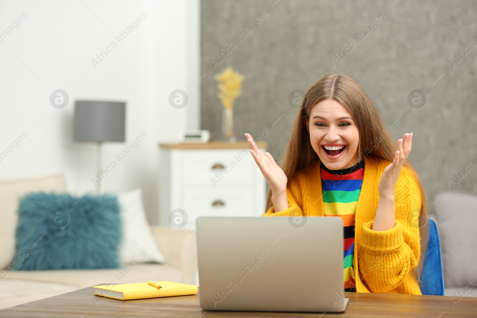 Photo of Happy young woman playing online lottery using laptop at home