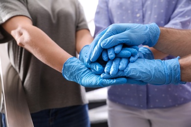 People in blue medical gloves stacking hands on blurred background, closeup