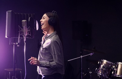 Photo of Young singer with microphone recording song in studio. Space for text