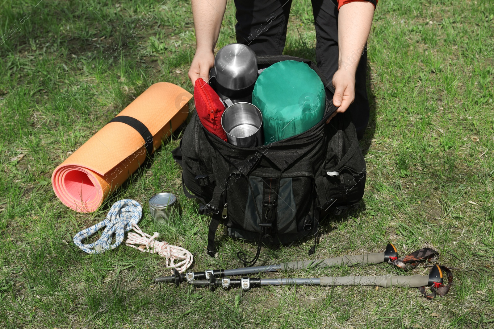 Photo of Hiker packing backpack outdoors, closeup. Mountain tourism