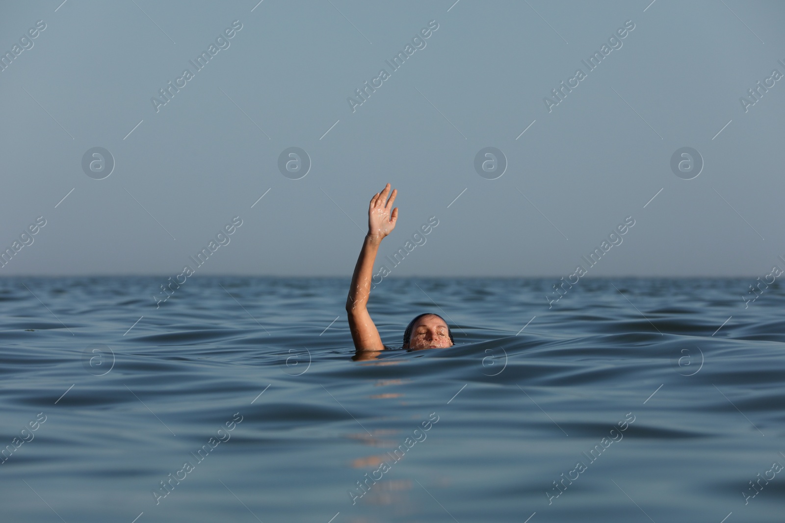 Photo of Drowning woman reaching for help in sea