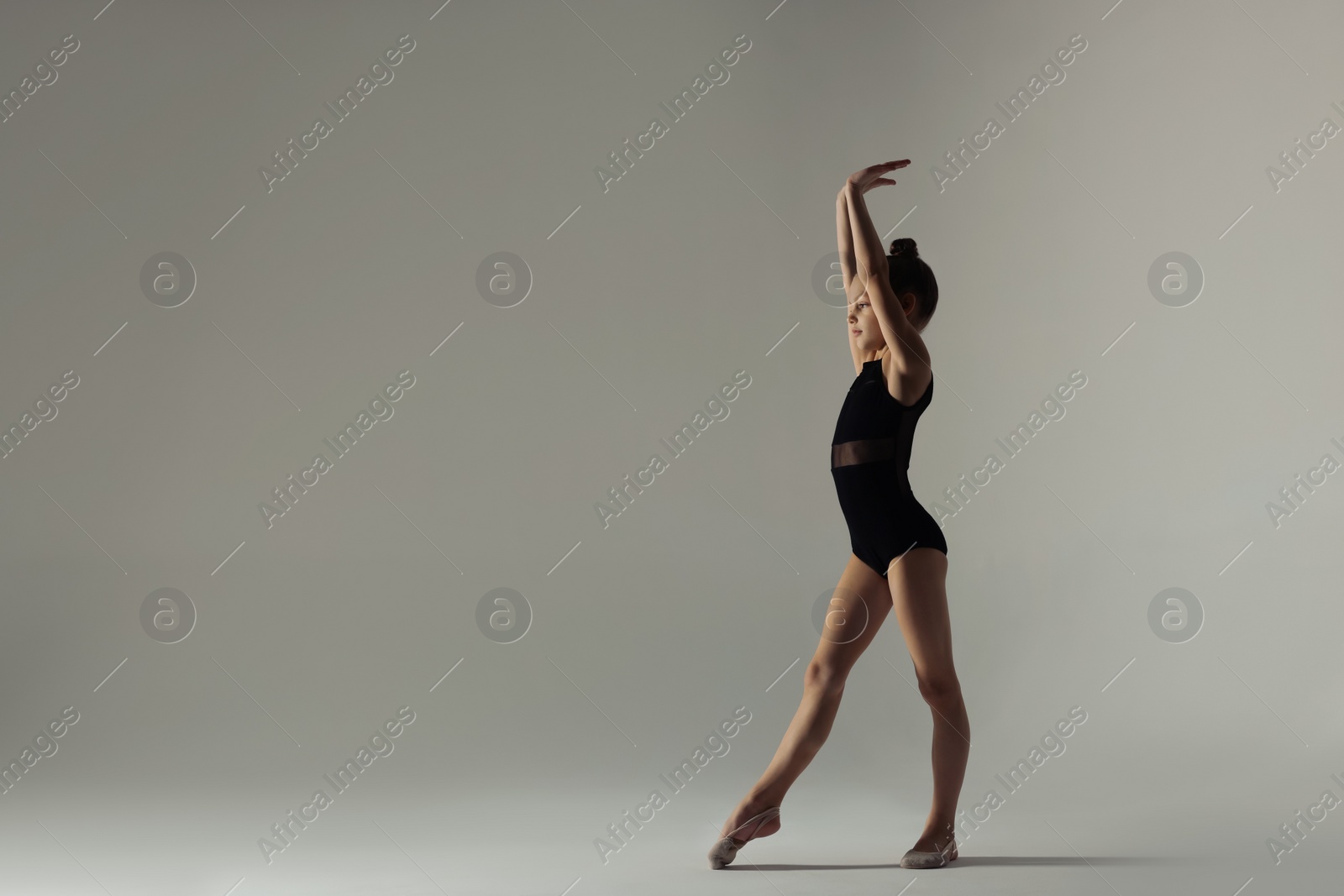 Photo of Cute little gymnast in leotard on white background