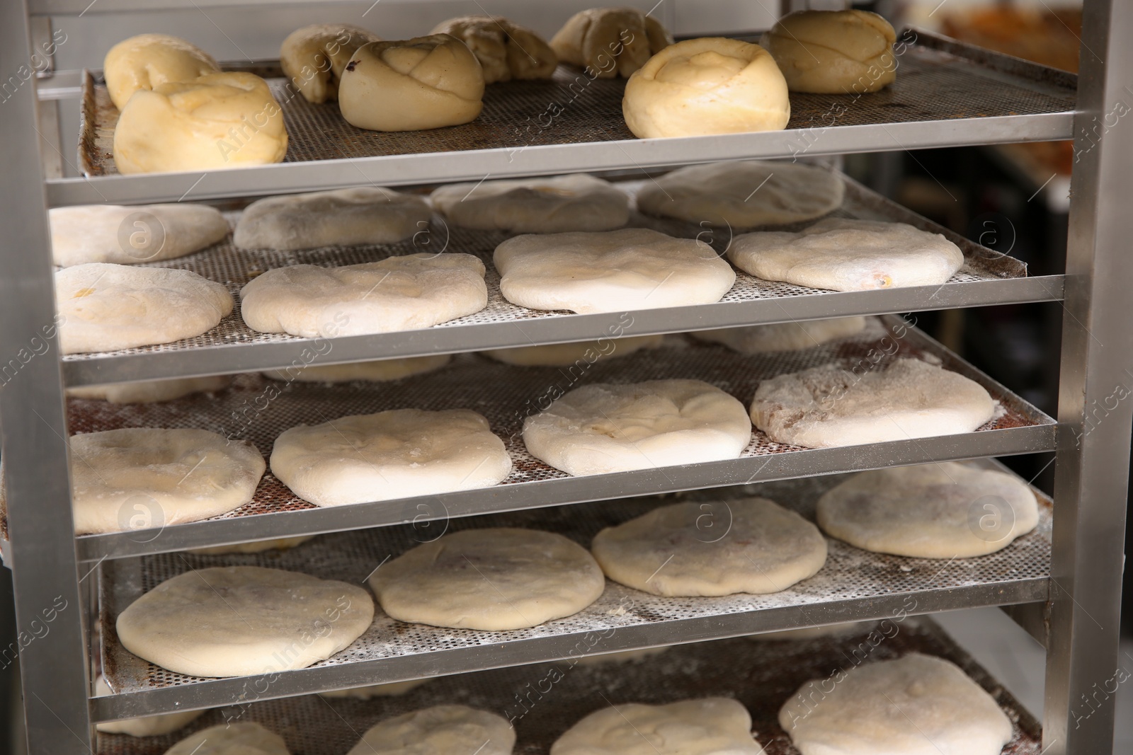 Photo of Rack with different unbaked pastries in workshop