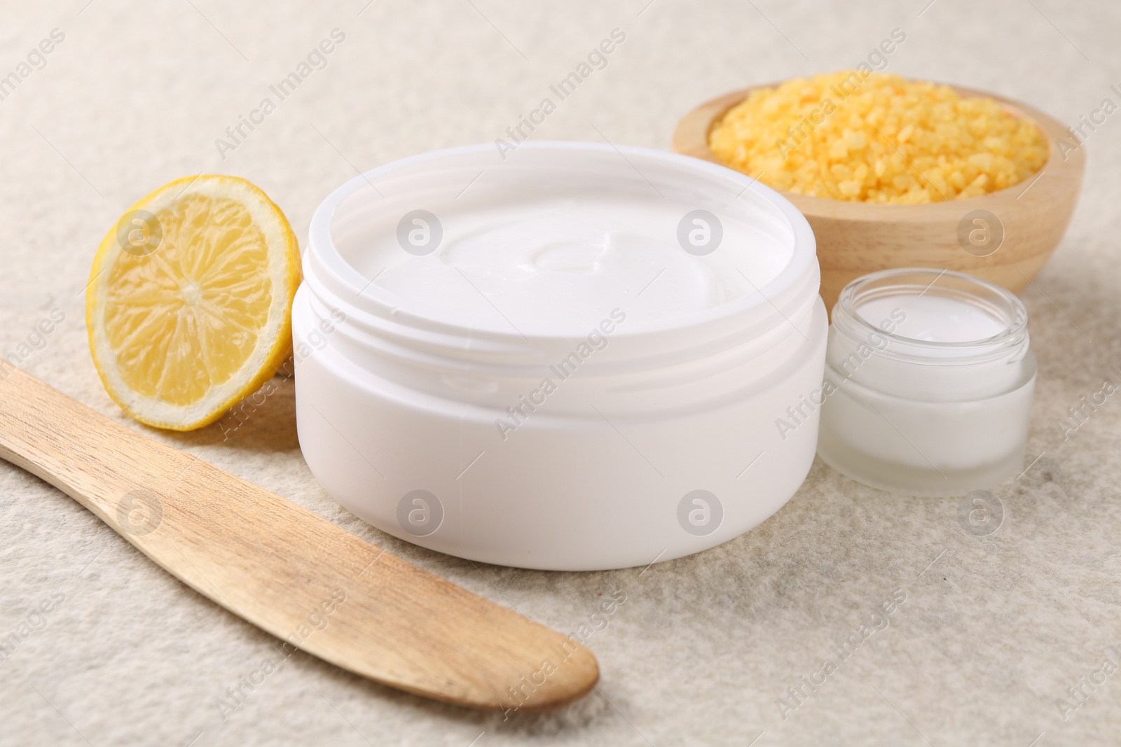 Photo of Composition with body care cream in open jars on light textured table, closeup