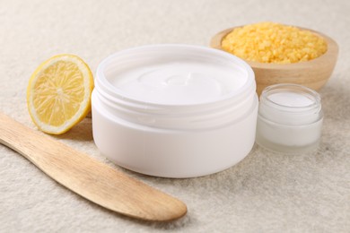 Photo of Composition with body care cream in open jars on light textured table, closeup