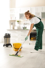 Photo of Professional janitor cleaning floor with mop in kitchen