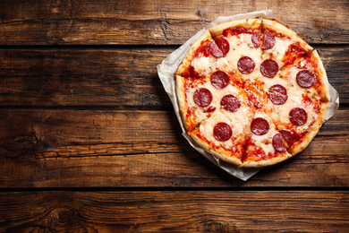 Photo of Hot delicious pepperoni pizza on wooden table, top view. Space for text