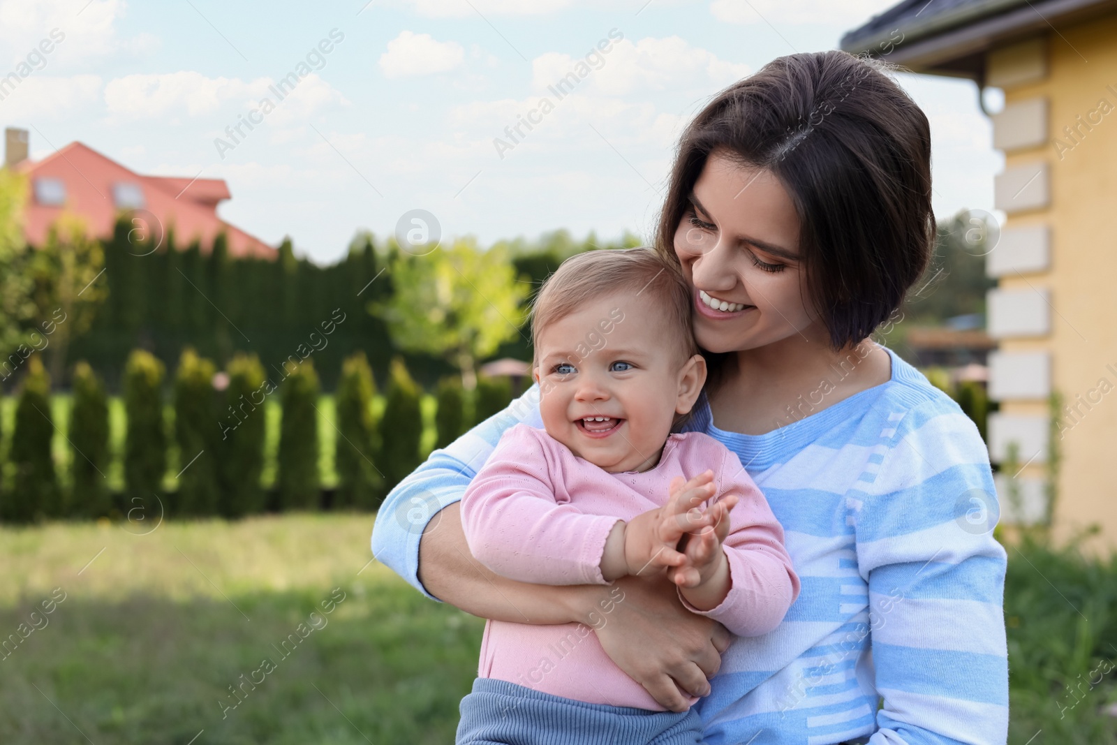 Photo of Happy mother with her cute baby at backyard on sunny day, space for text