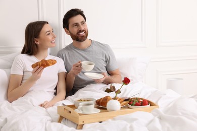 Photo of Happy couple having tasty breakfast in bed at home