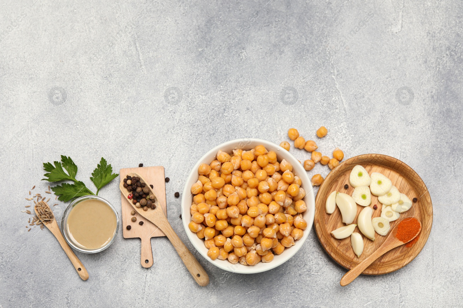 Photo of Delicious chickpeas and different ingredients on light grey table, flat lay with space for text. Cooking hummus