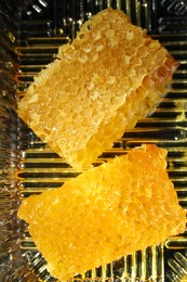 Photo of Natural honeycombs with tasty honey in plastic container, flat lay