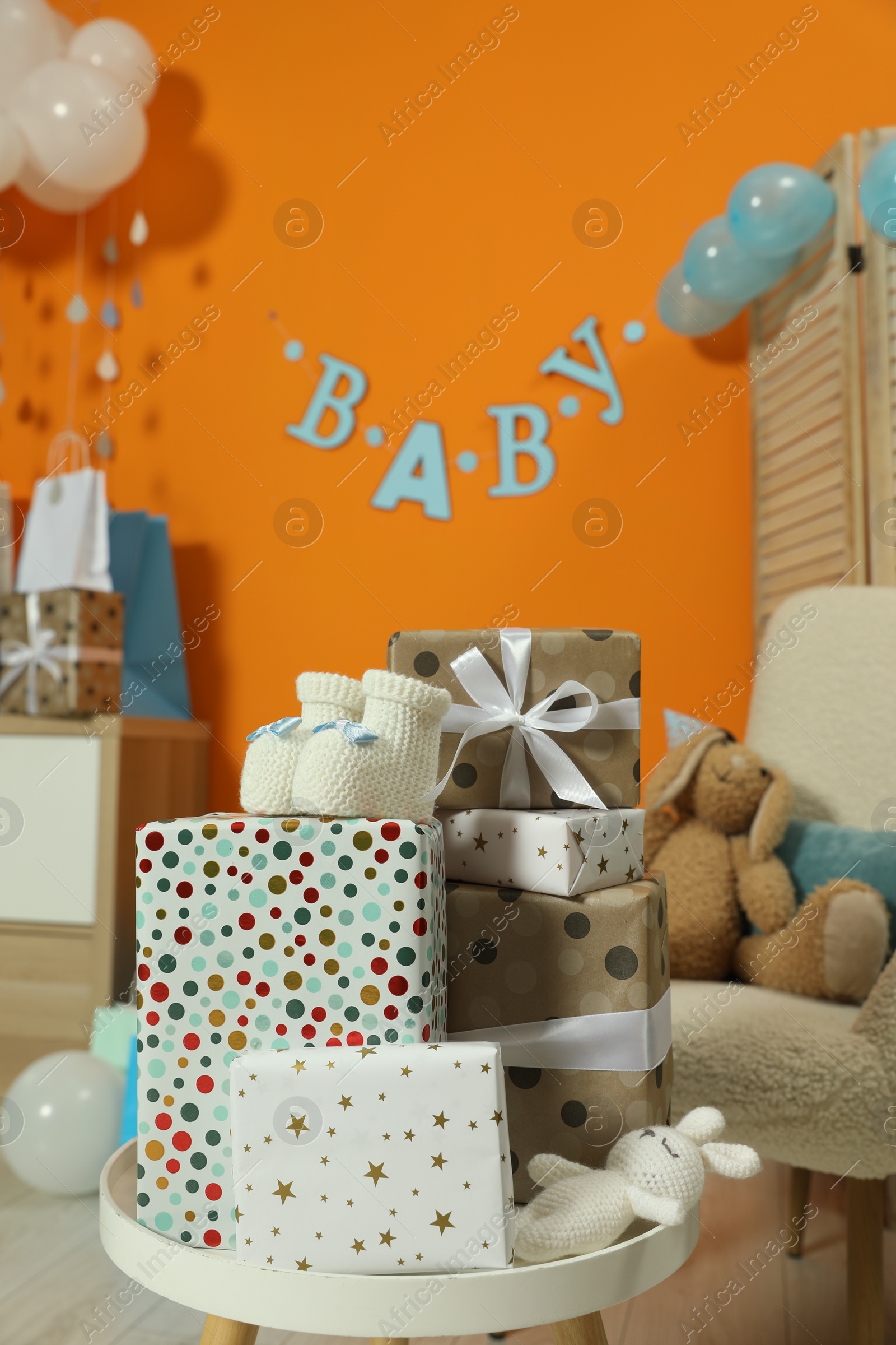 Photo of Baby shower party. Festive decor, gift boxes, booties and toys in stylish room, space for text