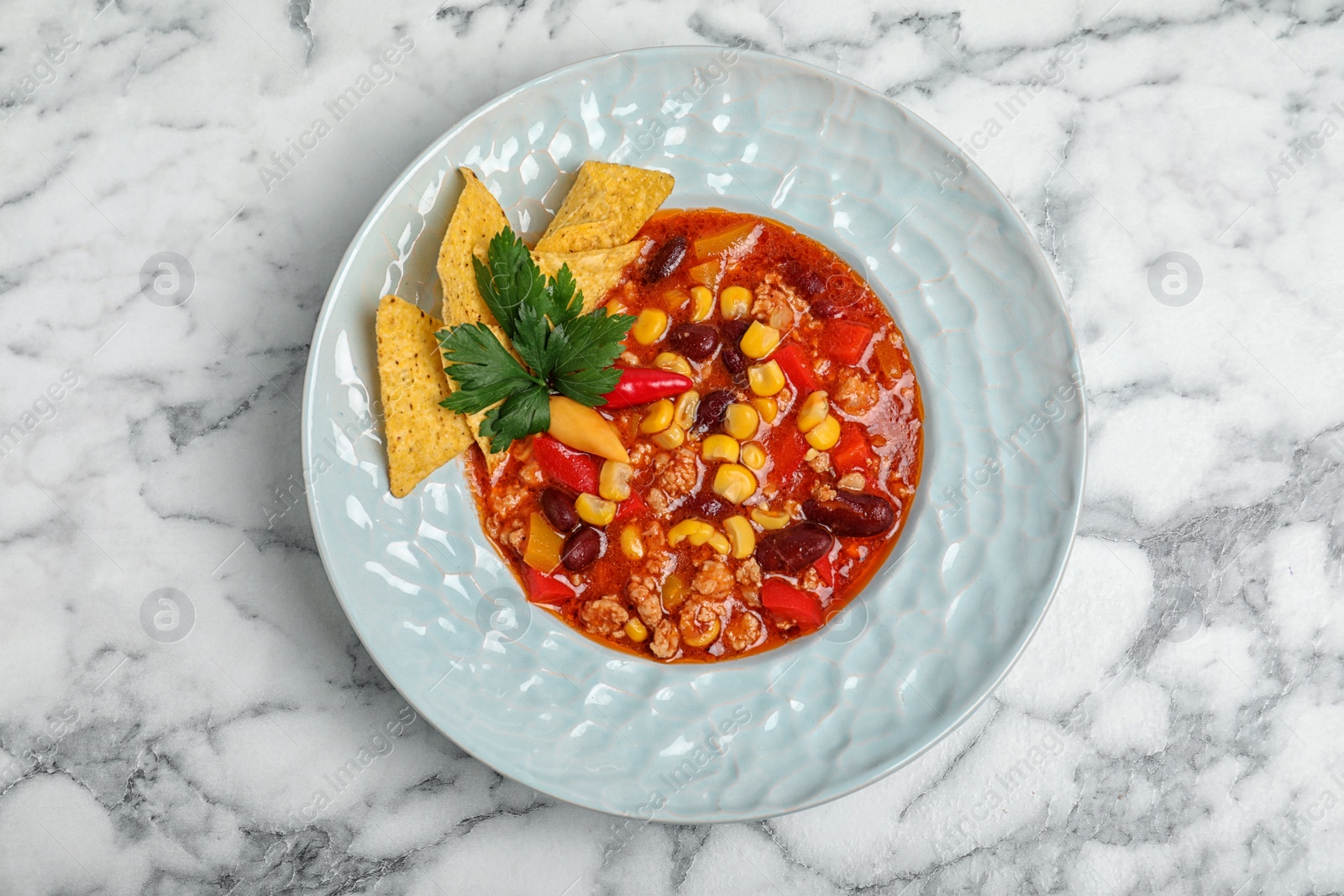 Photo of Plate with tasty chili con carne on marble background, top view