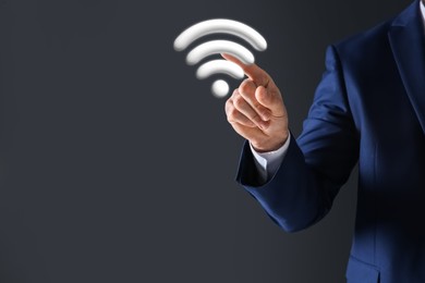 Image of Man touching Wi Fi symbol on digital screen against dark grey background, closeup