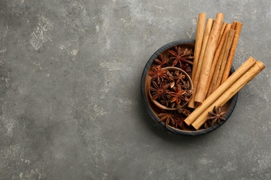 Photo of Aromatic cinnamon sticks and anise on grey table, flat lay. Space for text