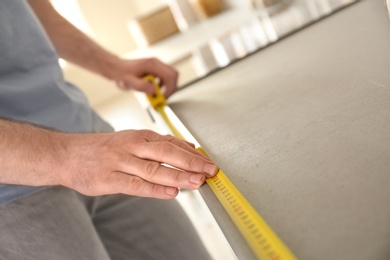 Man measuring kitchen furniture indoors, closeup. Construction tool