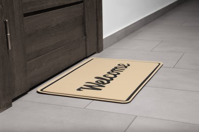 Photo of Beautiful beige doormat with word Welcome on floor near entrance