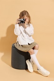 Photo of Fashion concept. Stylish girl with camera on pale orange background