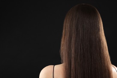 Photo of Woman with brunette hair on black background, back view. Space for text