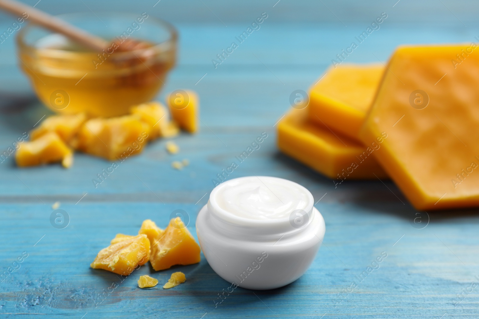 Photo of Cream with natural beeswax component on blue wooden table