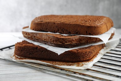 Photo of Layers of homemade chocolate sponge cake on white wooden table