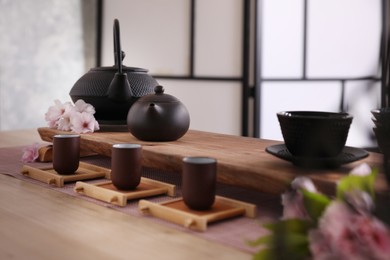 Photo of Beautiful set for traditional tea ceremony and sakura flowers on wooden table