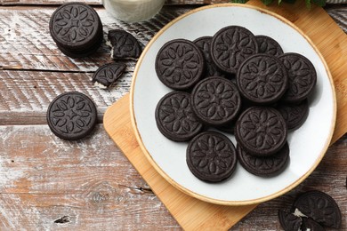 Photo of Plate with tasty sandwich cookies on wooden rustic table, flat lay