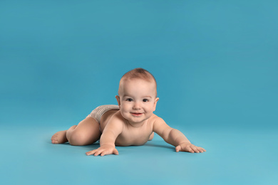 Photo of Cute little baby in diaper on light blue background