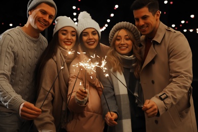 Group of people holding burning sparklers at night