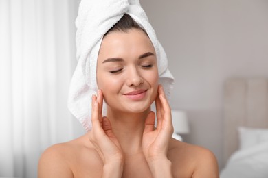 Photo of Beautiful young woman with hair wrapped in towel at home