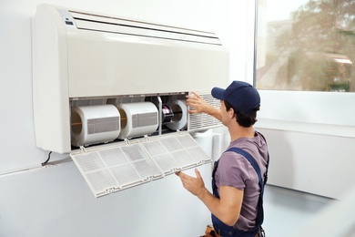 Photo of Technician installing and checking air conditioner indoors
