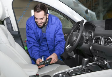 Photo of Worker vacuuming automobile seat, view from inside. Car wash service