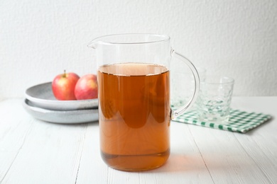 Jug with fresh apple juice on wooden table