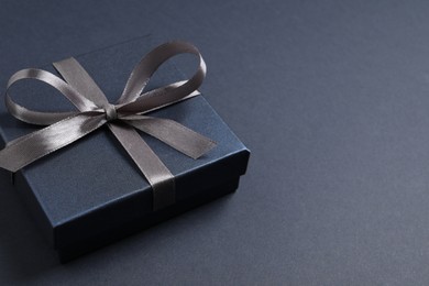 Beautiful gift box with bow on black background, space for text