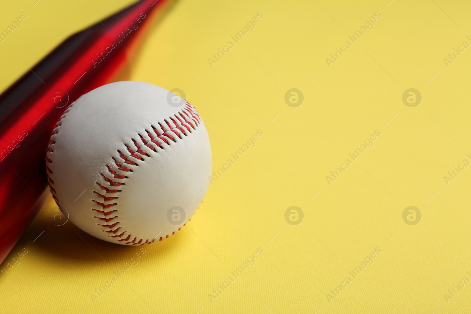 Photo of Baseball bat and ball on yellow background, closeup. Space for text