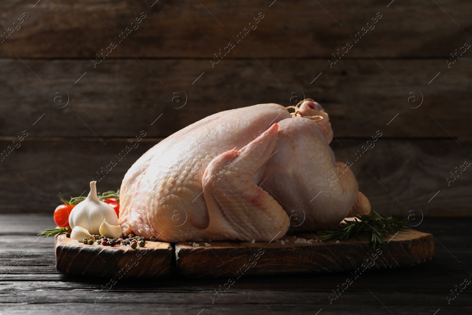 Photo of Board with raw turkey and ingredients on wooden table