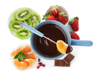 Photo of Fondue pot with dark chocolate, fruits and berries on white background, top view