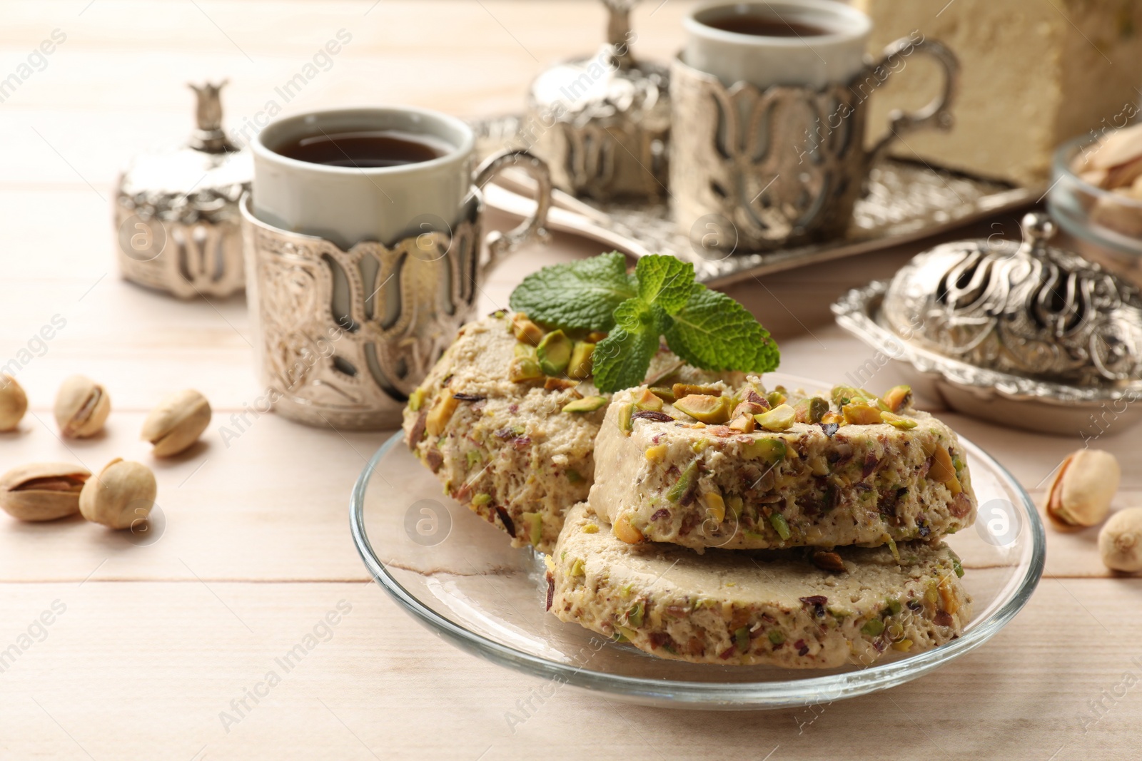 Photo of Tasty halva with pistachios and mint served on wooden table