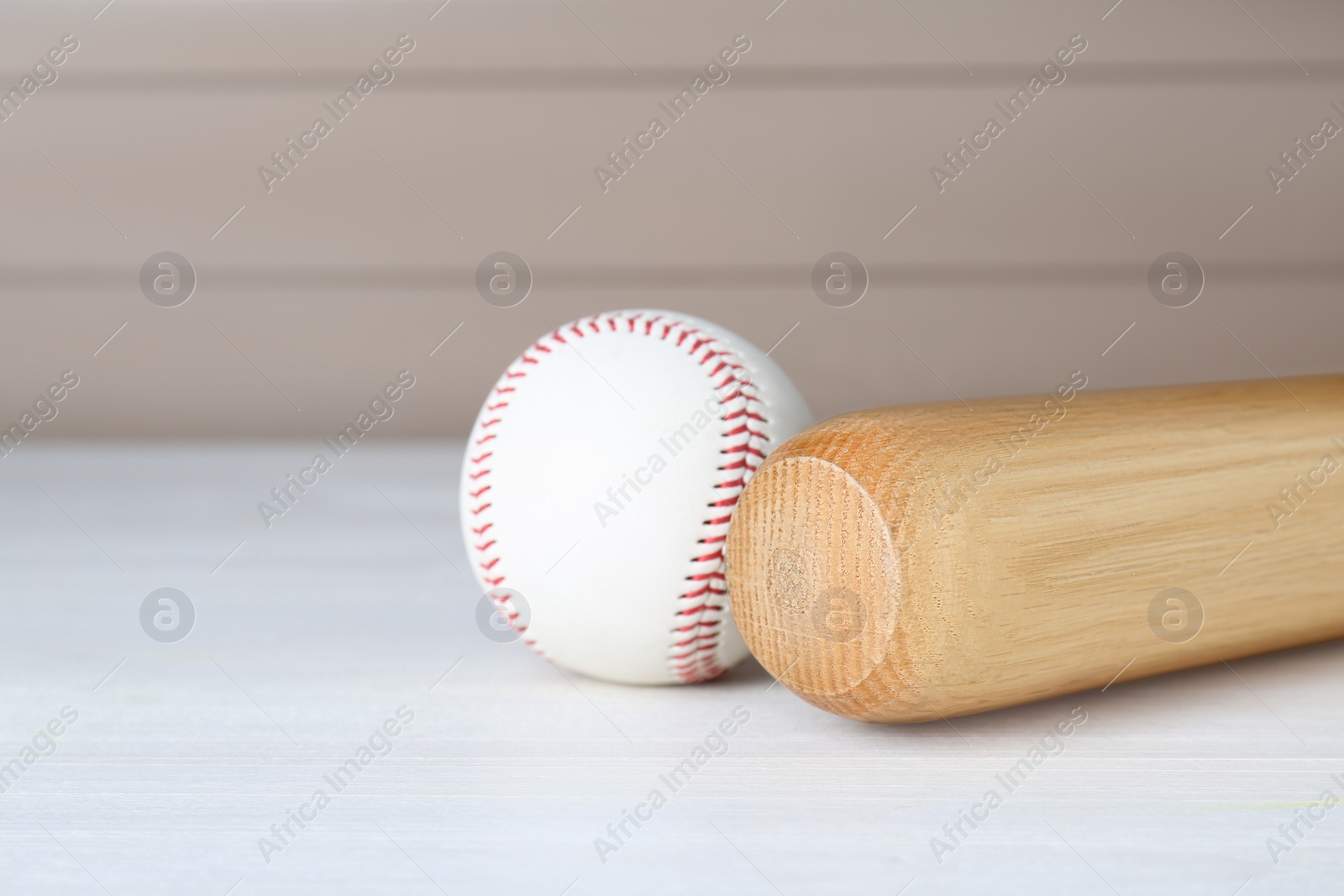 Photo of Baseball bat and ball on white wooden table, space for text. Sports equipment